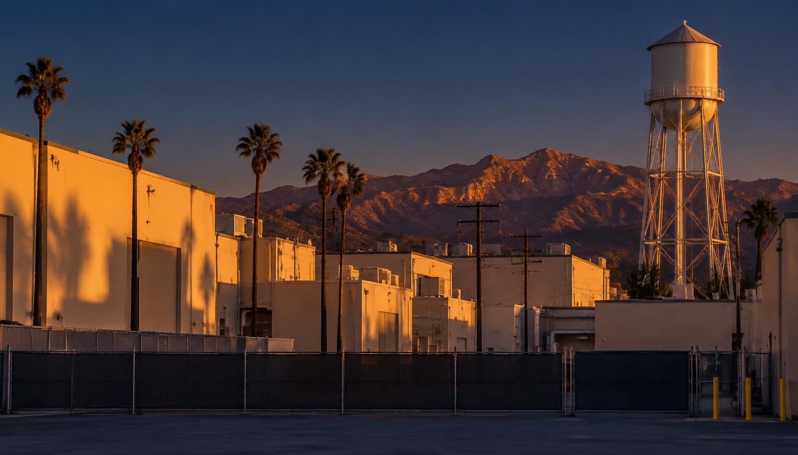 Burbank studio district soundstages and a water tower at dusk with foothills behind